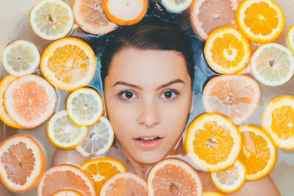 Woman's face in water surrounded by orange, lemon, and grapefruit slices