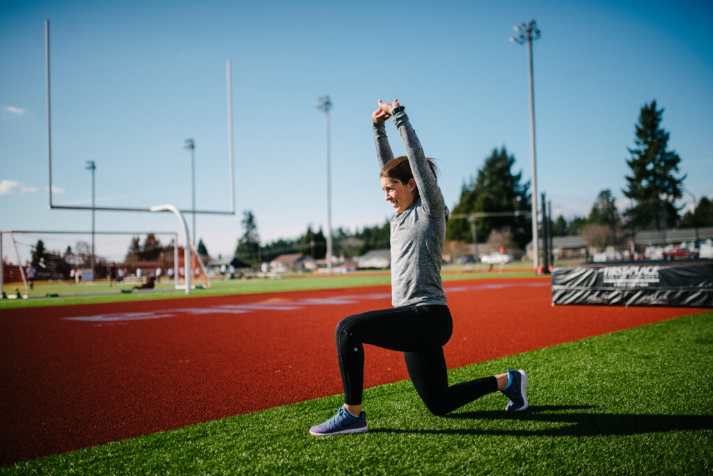 Woman in a runner's stretch on a track field.