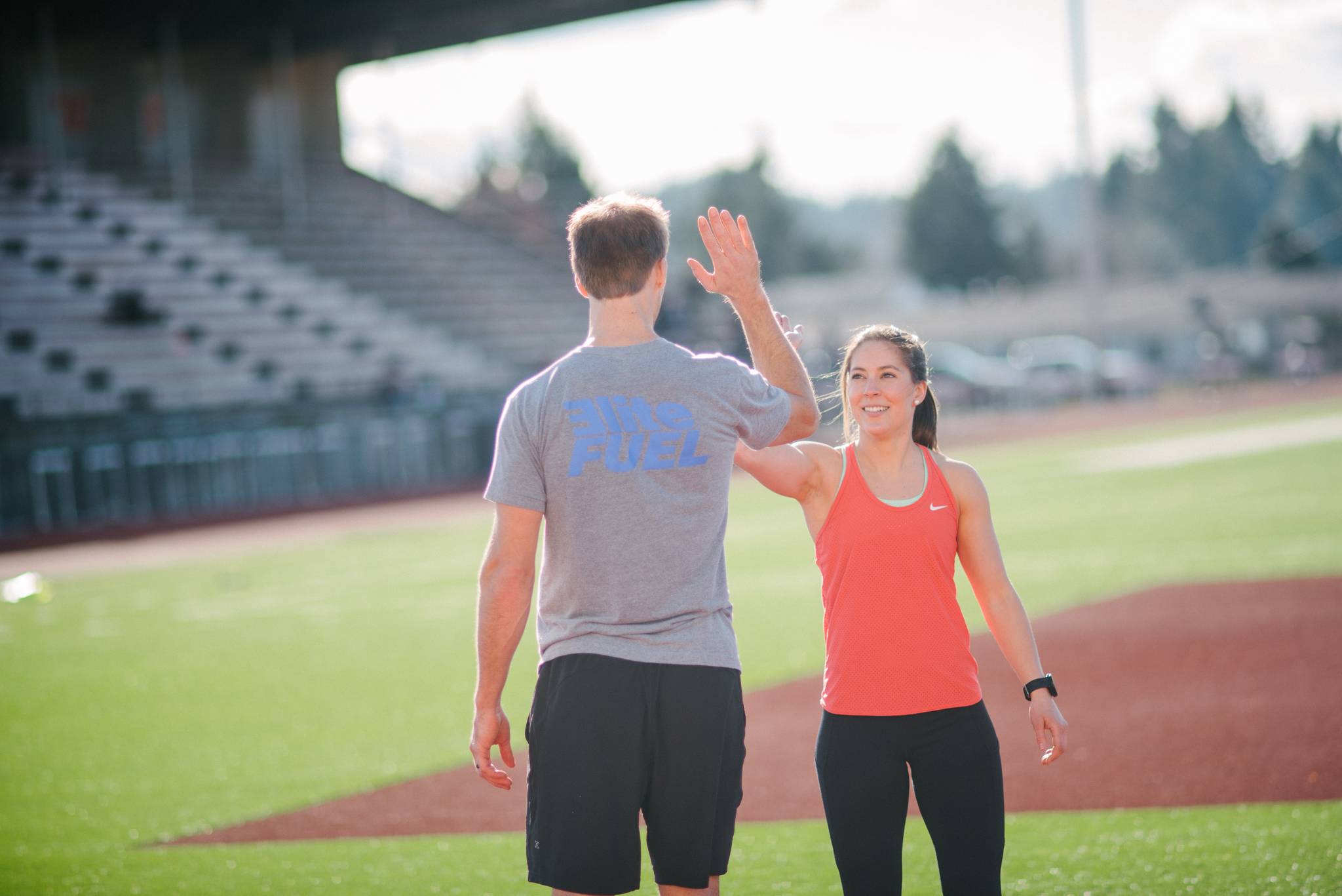 Man giving woman a high five on a track field