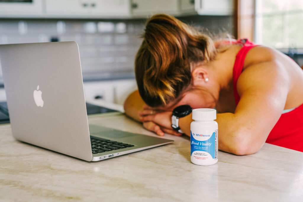 Woman sleeping computer with a bottle of Blood Vitality iron supplement